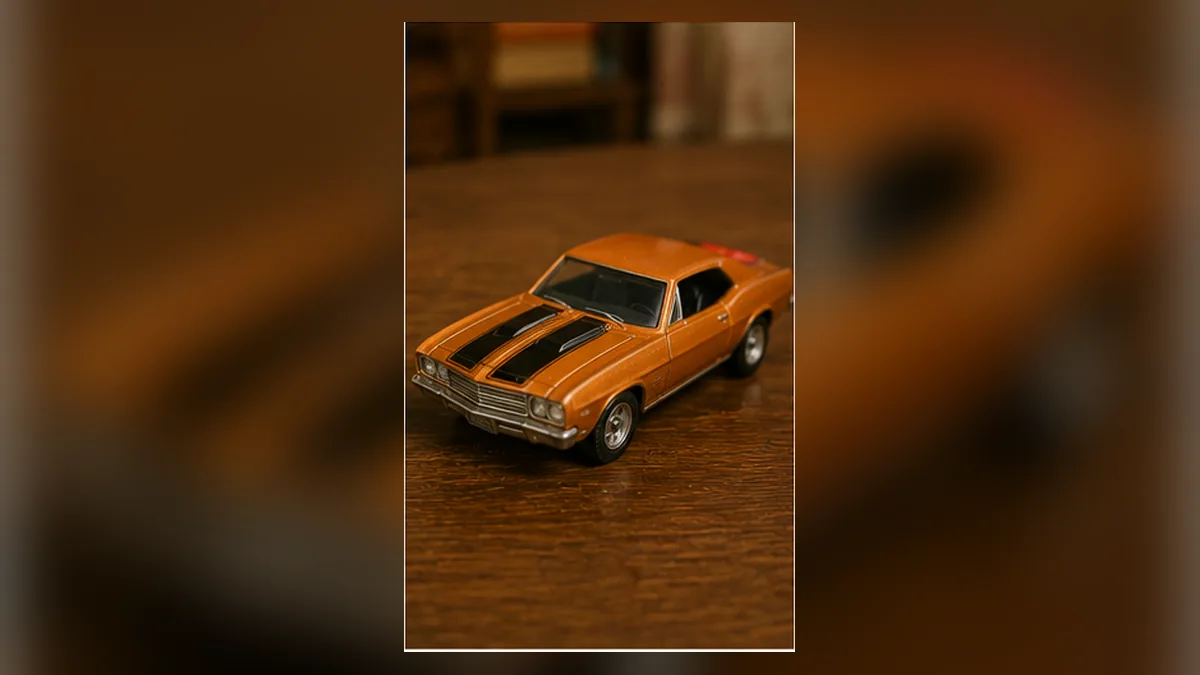 A detailed orange die-cast toy car on a polished wooden table