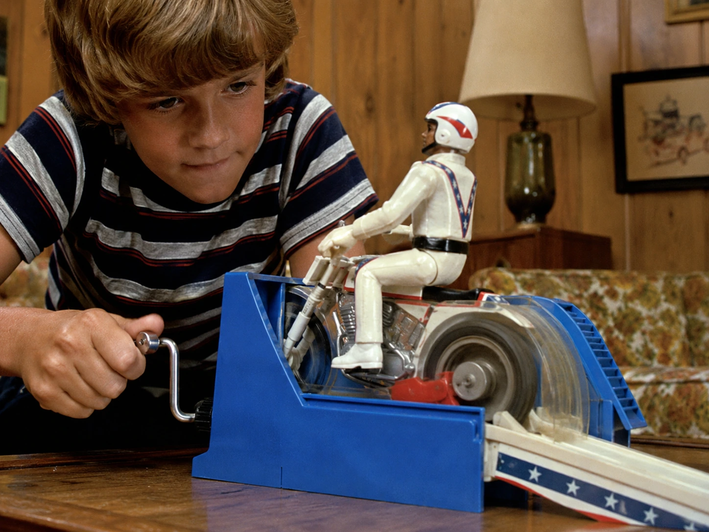 Child turning the hand crank while the rear wheel of an Evel Knievel stunt motorcycle spins inside the energizer