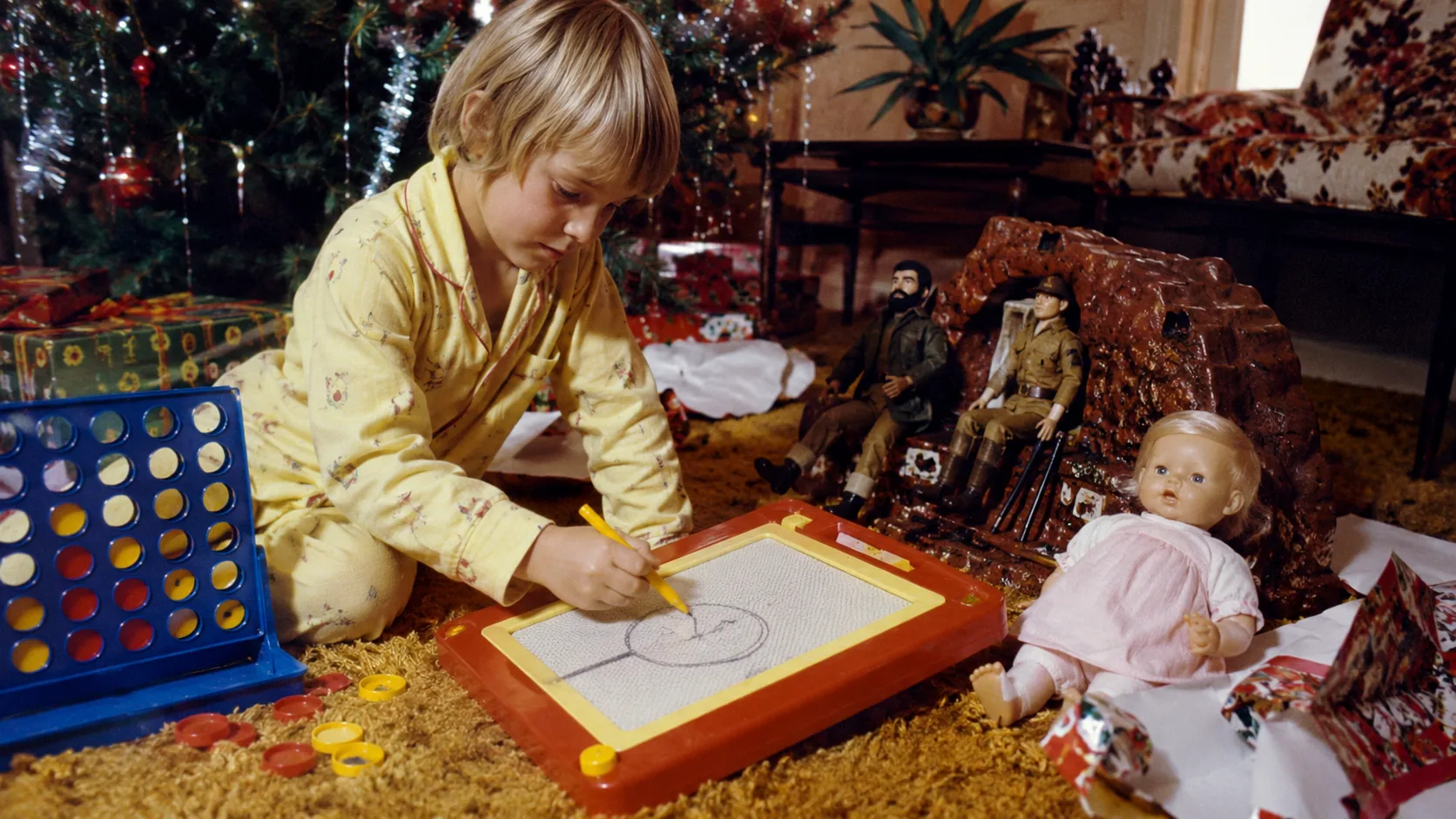 Child drawing with a Magna Doodle beside Christmas toys in 1974
