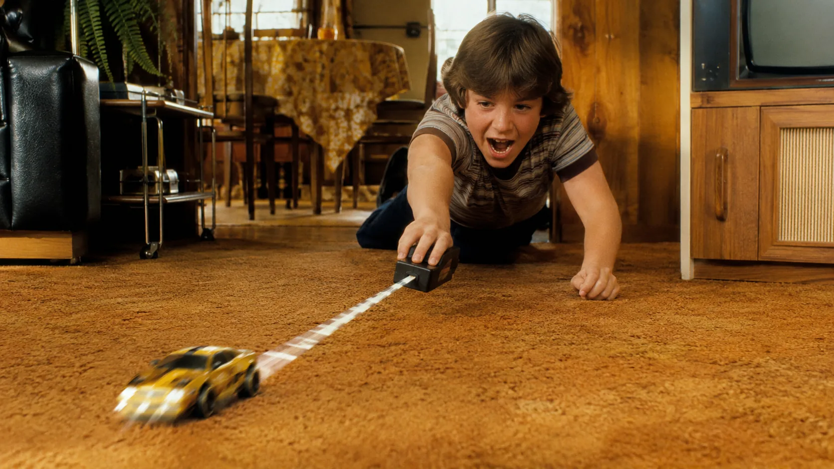 A child launching an SSP Racer across shag carpet in a 1970s family room