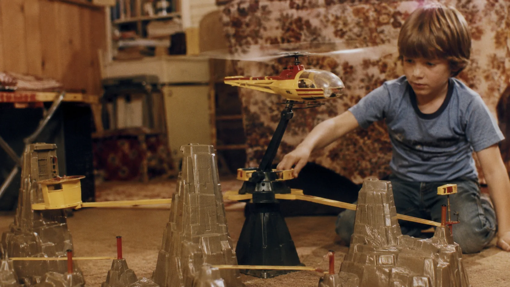 A child flying a VertiBird helicopter around a 1970s plastic playset