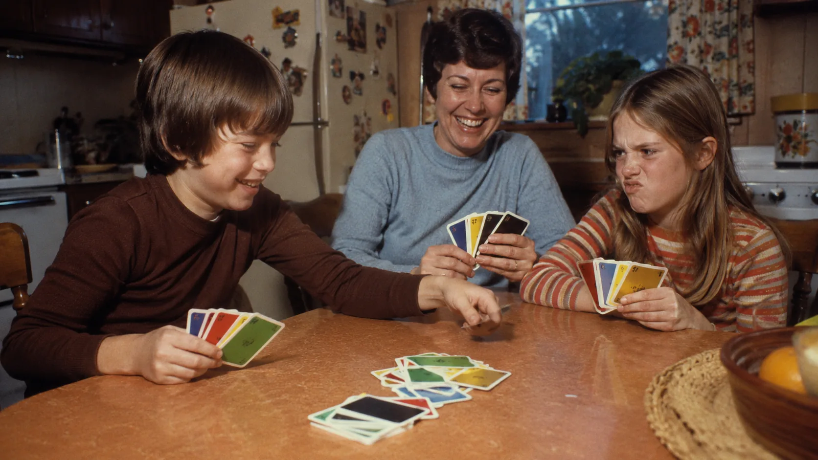 A family playing UNO around a 1970s kitchen table