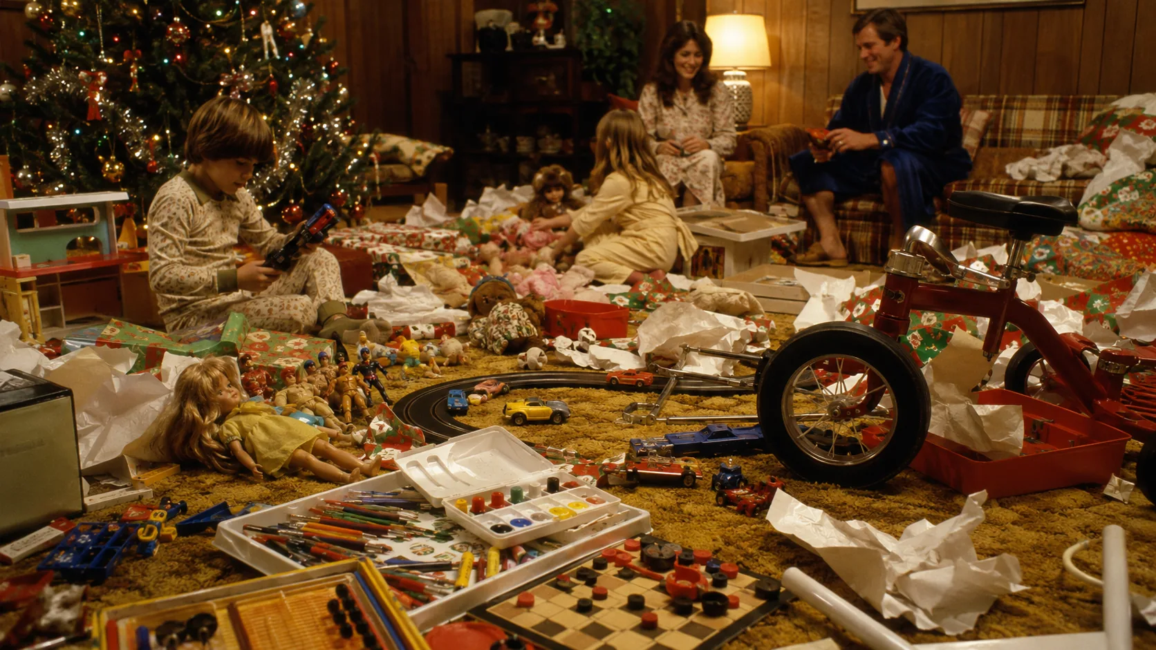 1970s family room covered with wrapping paper and newly opened Christmas toys