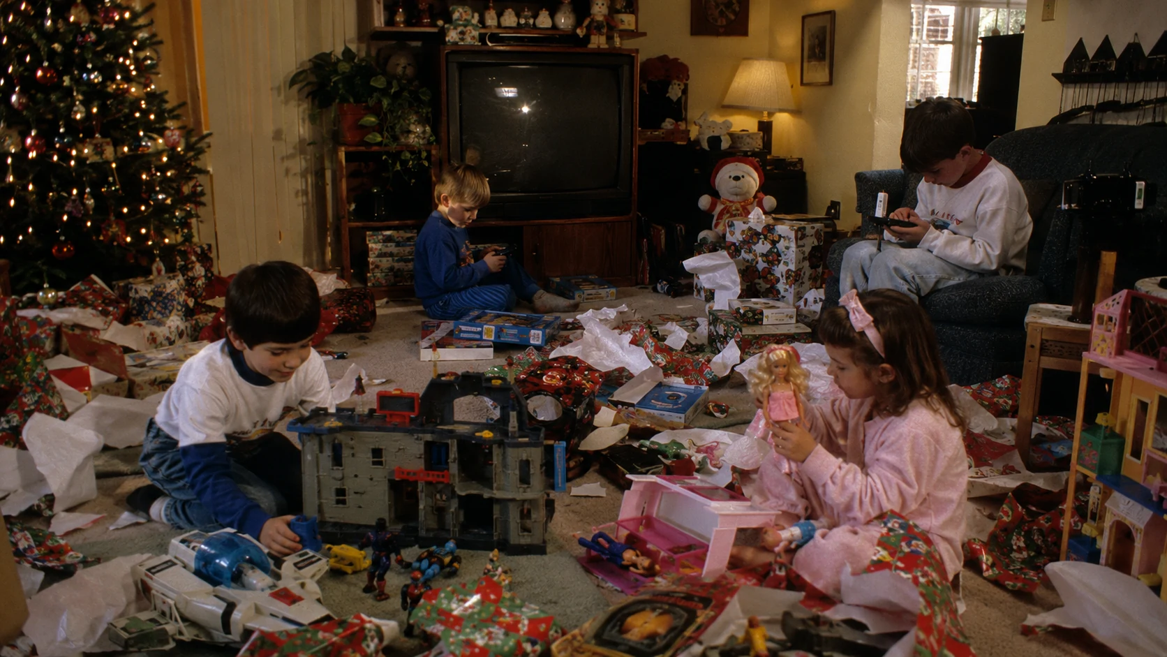 Parent surrounded by batteries instructions and an electronic toy on Christmas morning