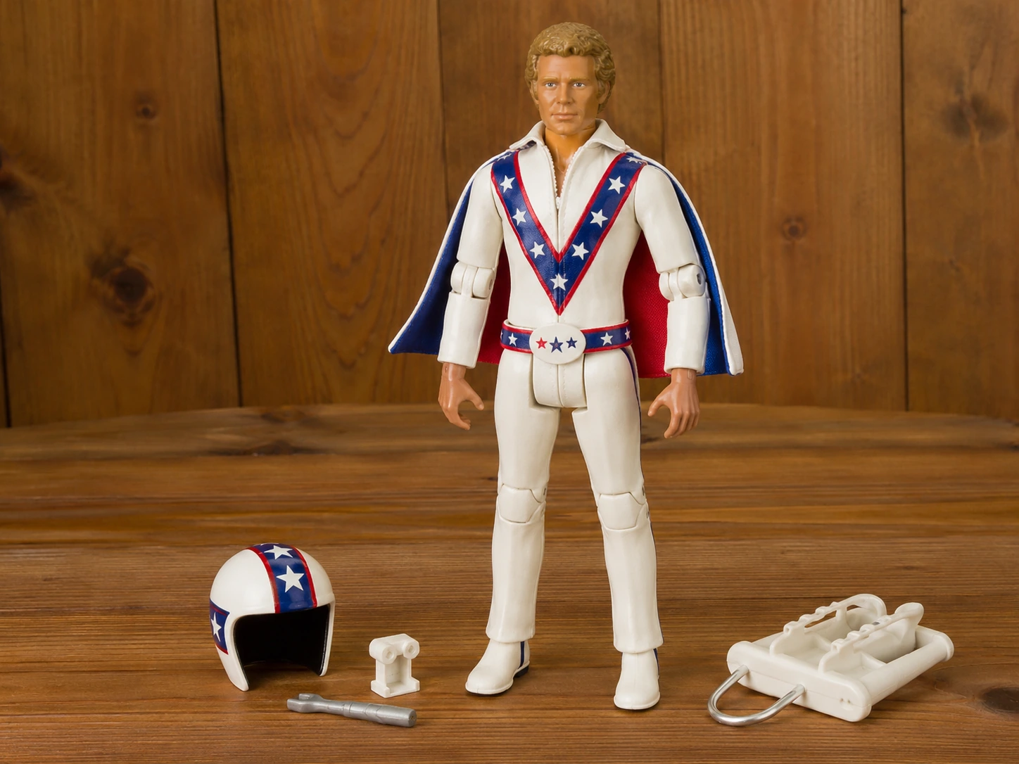 Vintage-style Evel Knievel action figure in a white patriotic jumpsuit with helmet and accessories