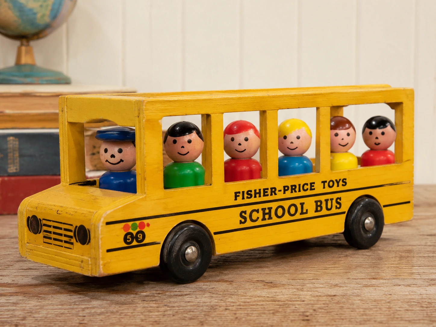 Vintage-style wooden yellow Fisher-Price school bus with removable round-headed riders