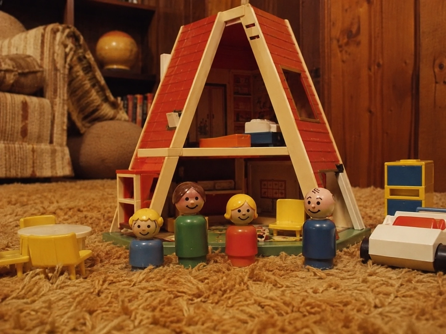 Classic A-frame Play Family House opened on shag carpet with family figures, furniture and car