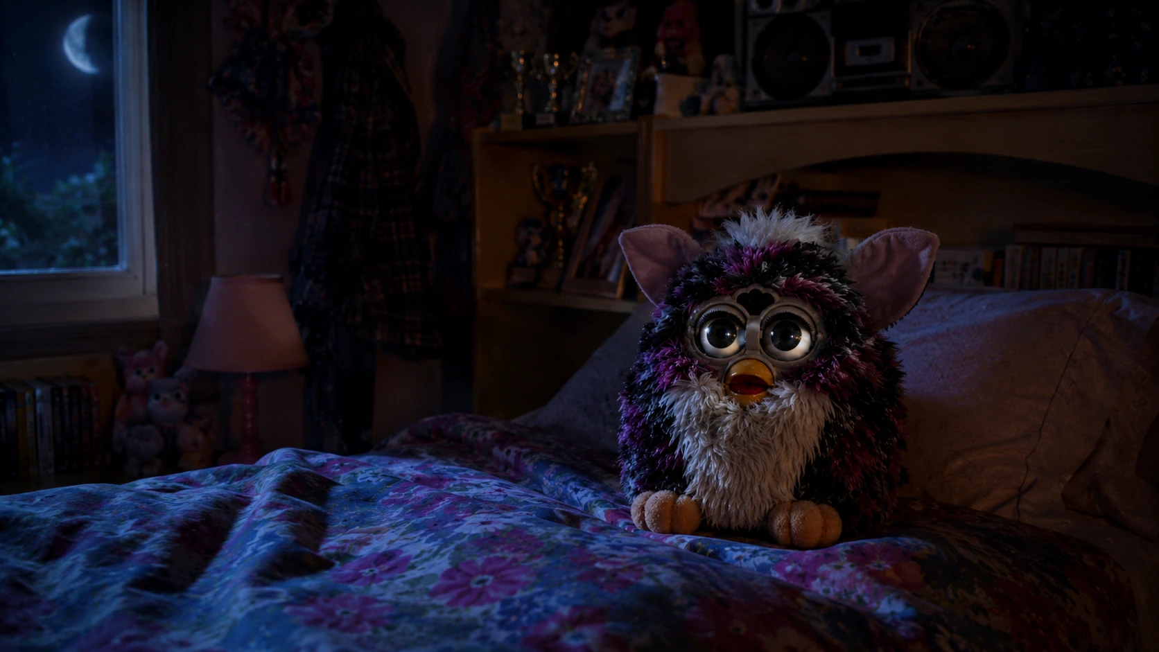 Furby sitting awake on floral bedding in a dark late-90s bedroom at night