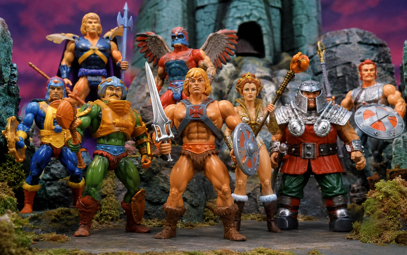Lineup of colorful heroic 1980s fantasy action figures posed together in front of an ancient castle.