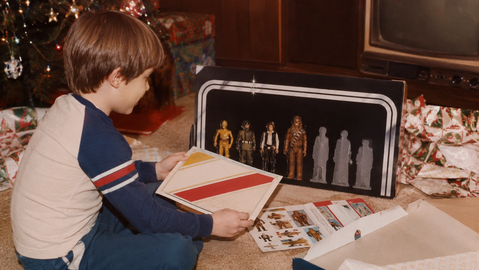 A child on Christmas morning examining an Early Bird-style display stand, paperwork and the first promised space figures