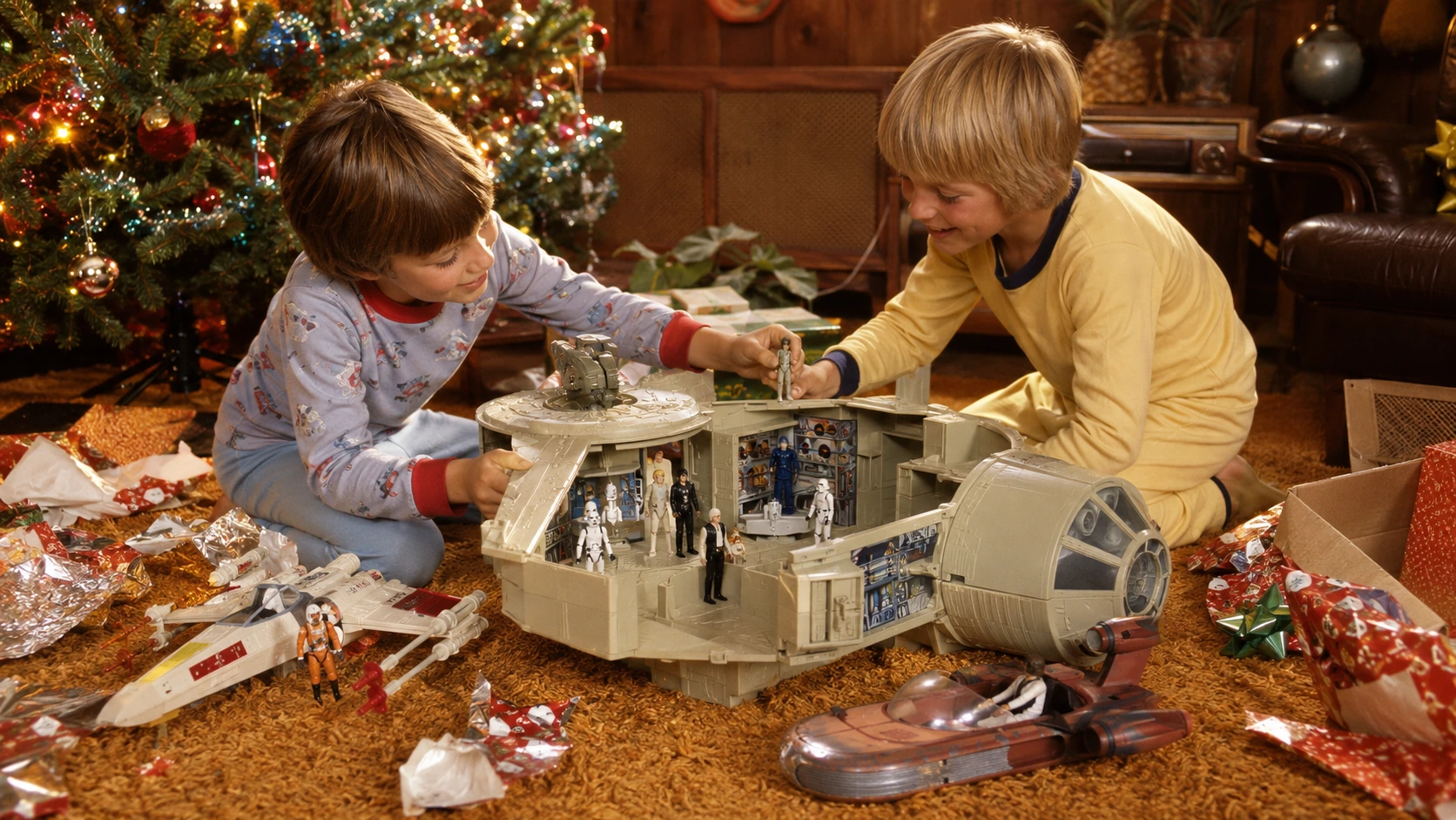 Two children playing with a large open space freighter, figures and starfighters beside a Christmas tree in 1979