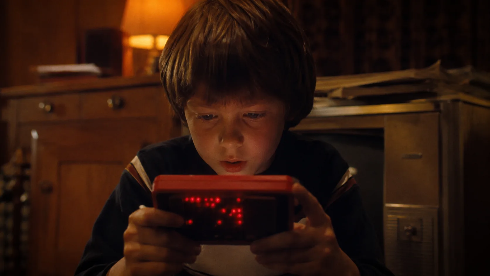 A child concentrating on a handheld Merlin electronic game in the late 1970s