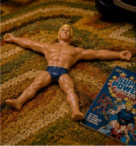 Modern Stretch Armstrong-style figure displayed beside nostalgic superhero material