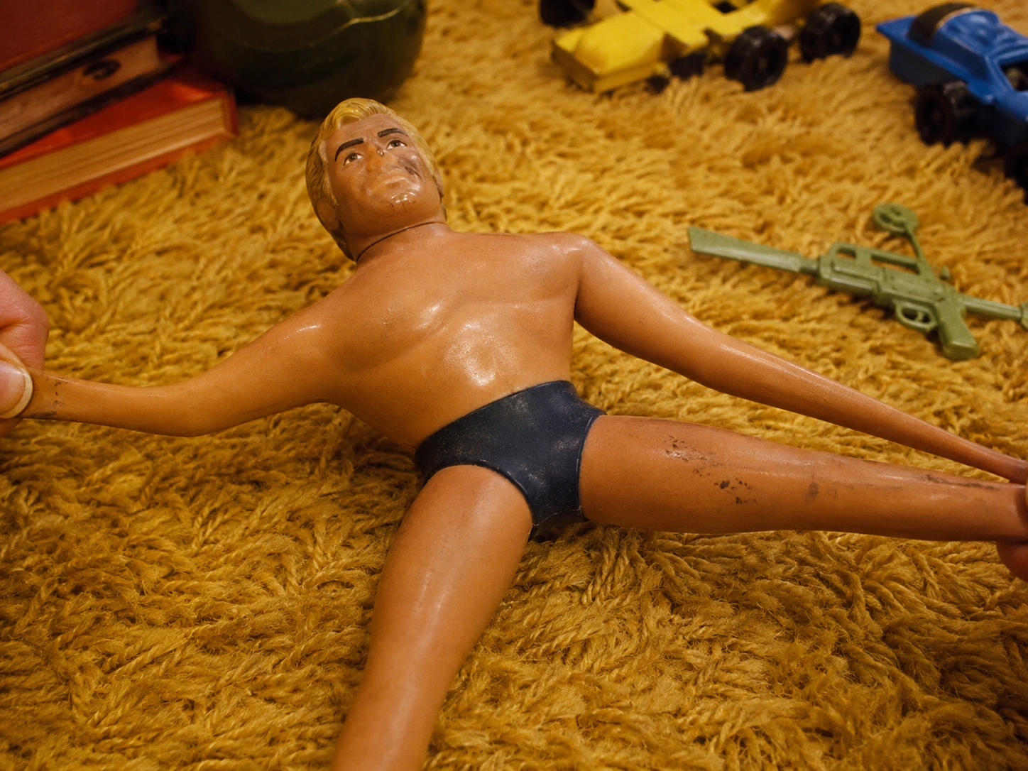 Close view of the original-style Stretch Armstrong sculpt, blond hair, face, muscular torso and dark trunks