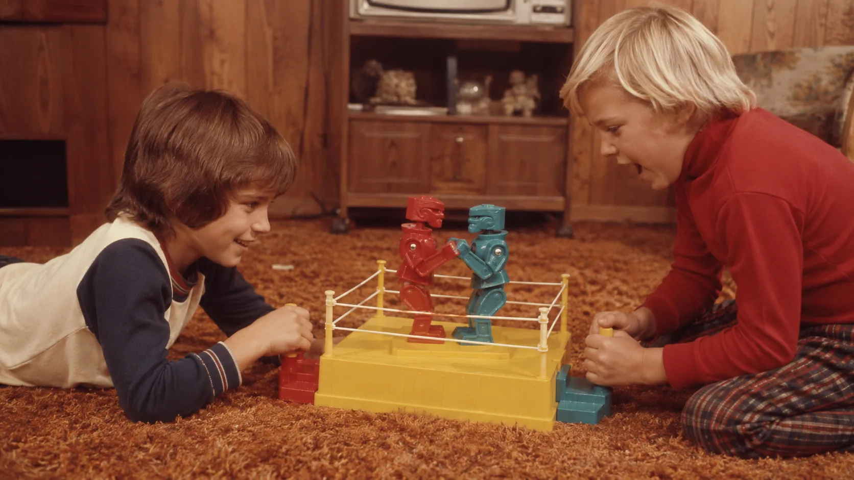 Two children battling with red and blue Rock 'Em Sock 'Em Robots on shag carpet
