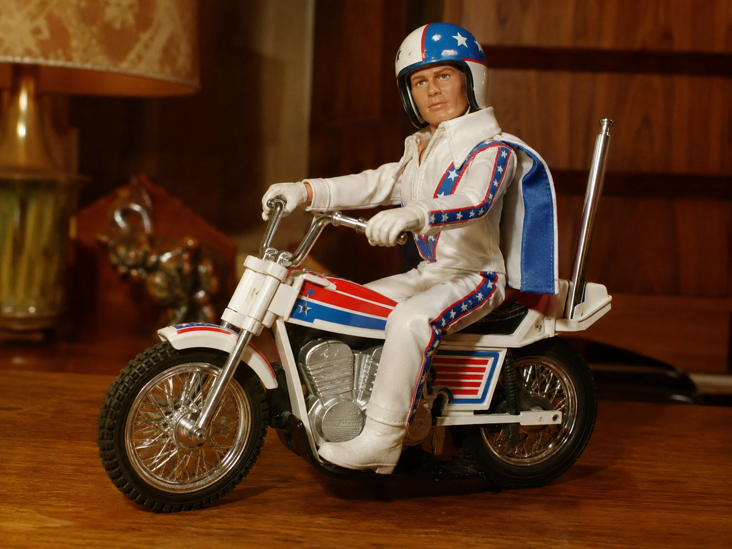 Close view of an Evel Knievel figure seated on a red white and blue stunt motorcycle