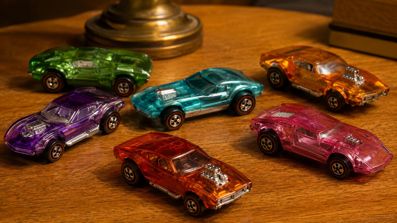 Translucent candy-colored toy cars in purple, aqua, orange, green, pink and red on a warm wooden table