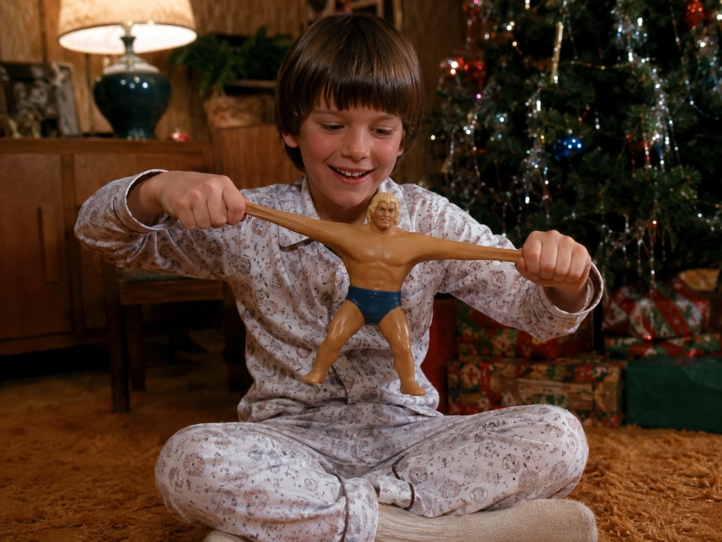 Child stretching Stretch Armstrong beside a decorated Christmas tree and opened presents in 1976