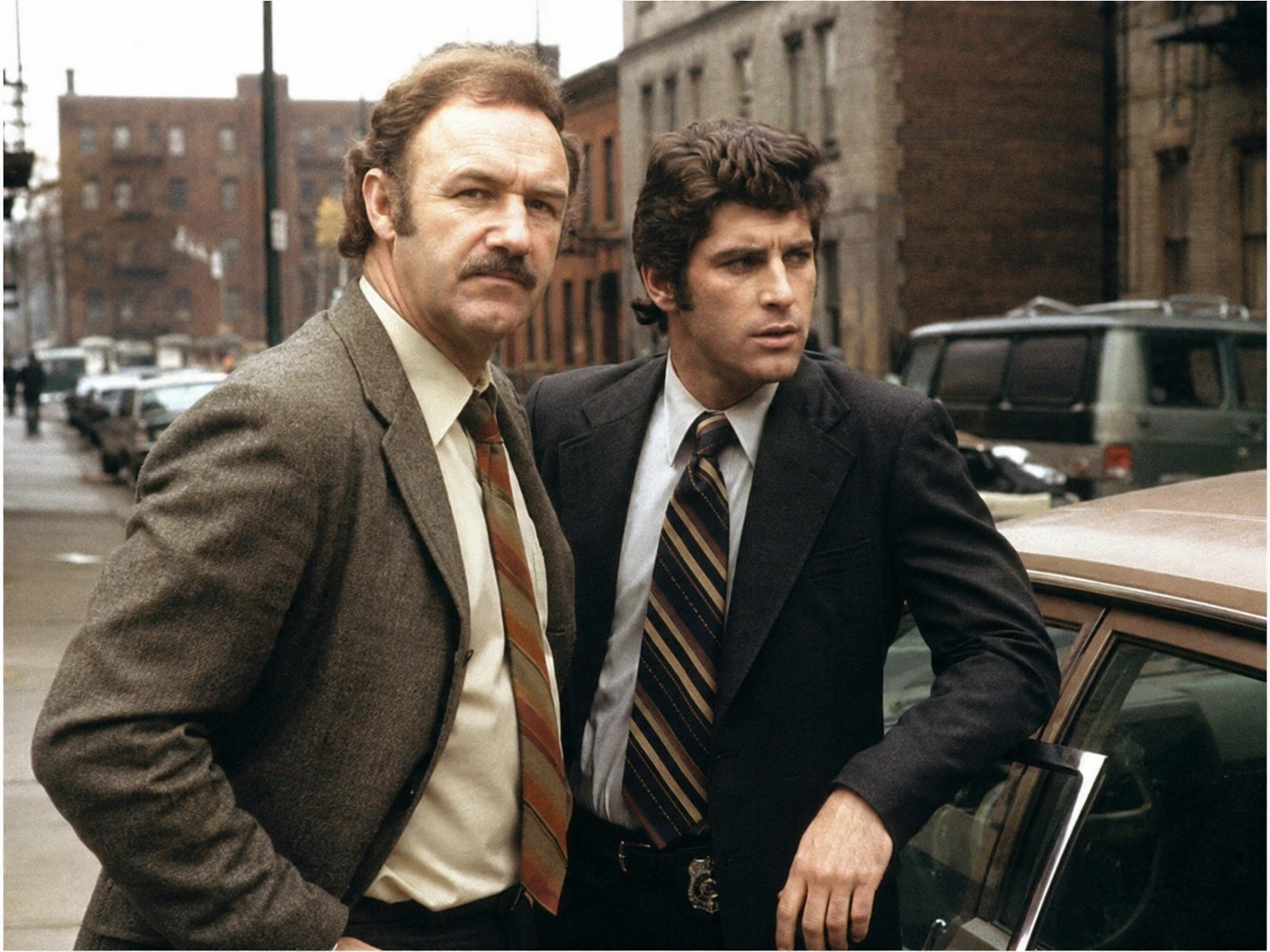 Period-style 1970s urban detective partners beside an unmarked car