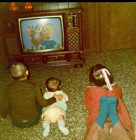 Child sitting close to a woodgrain television in the 1970s