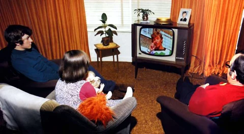 Family gathered around a woodgrain television watching a 1970s crime show