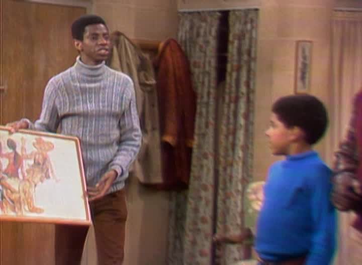 J.J. Evans standing beside one of his paintings on Good Times