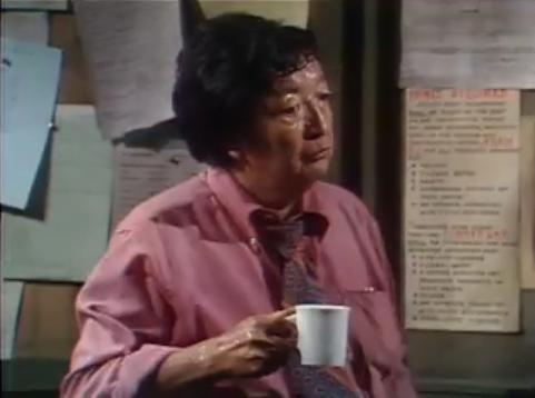 Jack Soo as Detective Nick Yemana at his desk in Barney Miller