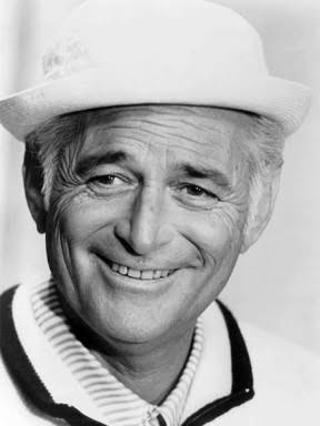 Norman Lear smiling in his familiar white hat