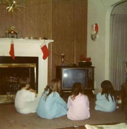 Child and family watching a CRT television in a period living room