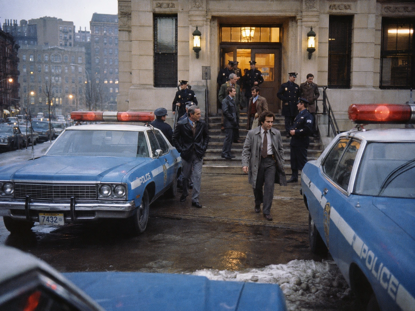 Period-style 1970s city police station with patrol cars on a rainy evening